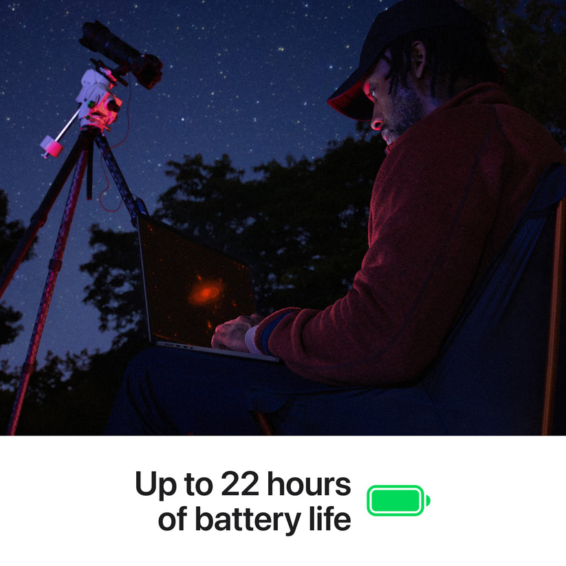 Person using a laptop with a telescope at night, under a starry sky.
