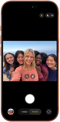 iPhone 17 Pro in Cosmic Orange, front, screen shows Center Stage front camera open with a group selfie of five people centered in frame