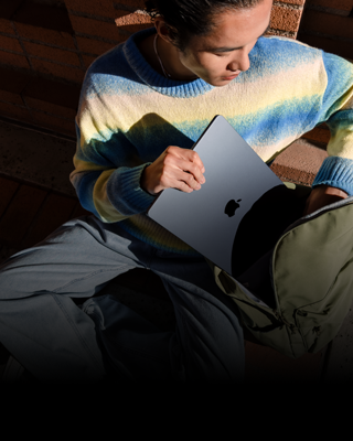 A person places their 15-inch MacBook Air in Midnight into their backpack